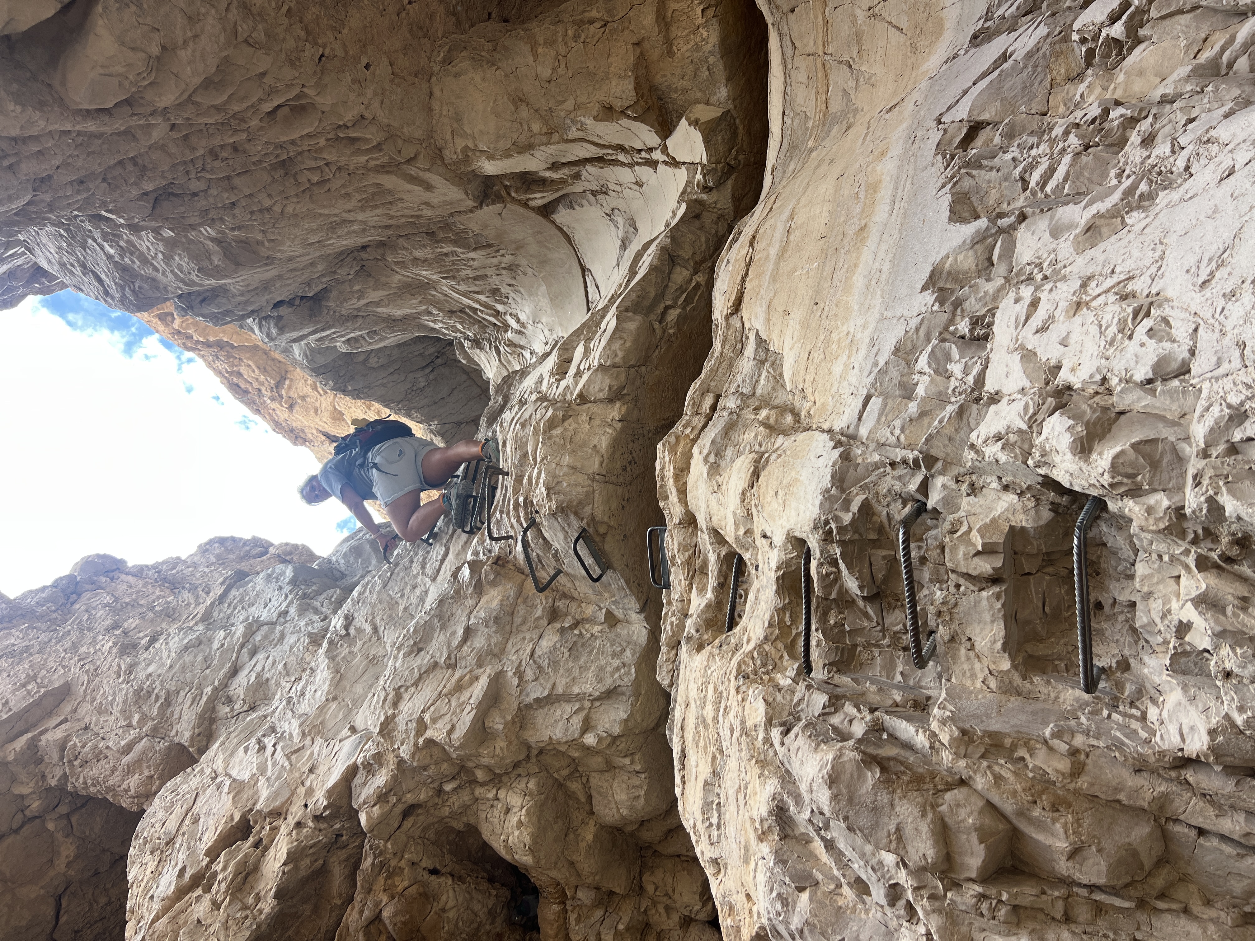 Hiker climbing iron ladder bolted into canyon wall, Og Stream waterfall