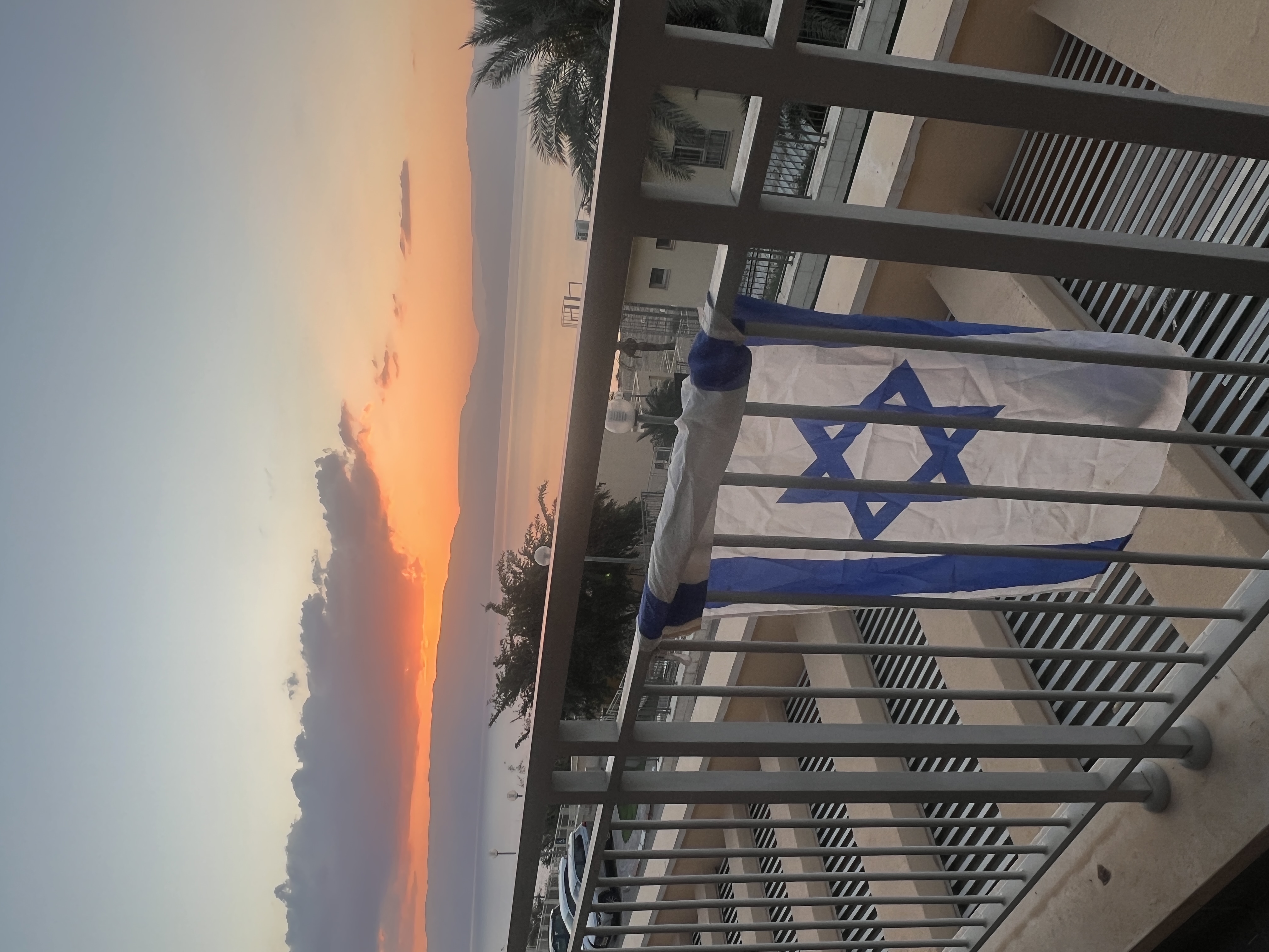 Israeli flag against dramatic orange sunrise sky, Memorial Day, Ein Gedi